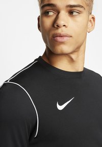 Zwart sportshirt met witte piping langs de schouders en een wit Nike swoosh-logo op de borst. Gladde, aansluitende stof.