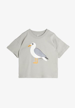T-shirt grigio a maniche corte con una grafica di un gabbiano. Il design include accenti arancioni, neri e bianchi su un morbido misto cotone.