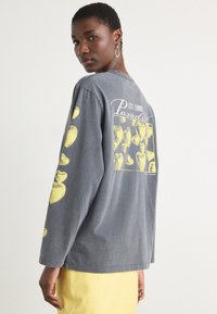 Long-sleeve gray t-shirt featuring yellow heart graphics on sleeves and back, with a text design reading "CITY SUMMER Paradise." Cotton material.