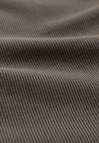 Primer plano de tela gris acanalada con pliegues suaves y textura visible en líneas verticales.