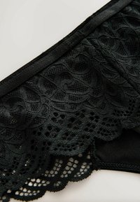 Čierne čipkované spodné prádlo má detailný vlnkový okraj s prekrasnými vzormi. Mäk materiál s kontrastnou hladkou časťou pod čipkou.