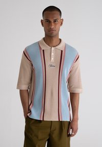 Lightweight knitted polo shirt in beige, blue, and red stripes. Features a collar and three buttons. Short sleeves and textured fabric.