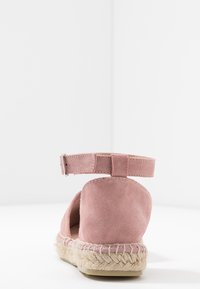 Różowe zamszowe espadryle na koturnie z paskiem na kostkę, plecioną jucie podeszwą, zaokrąglonym obcasem i otwartym tyłem. Gładka faktura w minimalistycznym stylu.