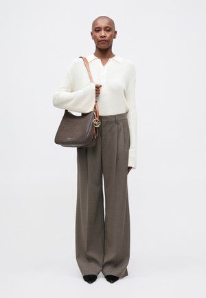 Suéter de canalé crema con mangas acampanadas, pantalones de pierna ancha grises y un bolso marrón con un detalle de logo. Zapatos negros de punta.