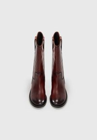 Botas de cuero marrón hasta el tobillo con un acabado suave, punta redondeada, paneles elásticos laterales y costuras de contraste a lo largo de las costuras.