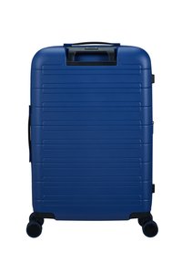 Valise rigide bleue avec texture en relief, une poignée supérieure et quatre roues pivotantes pour une mobilité facile. Comprend un zip noir et des accents.