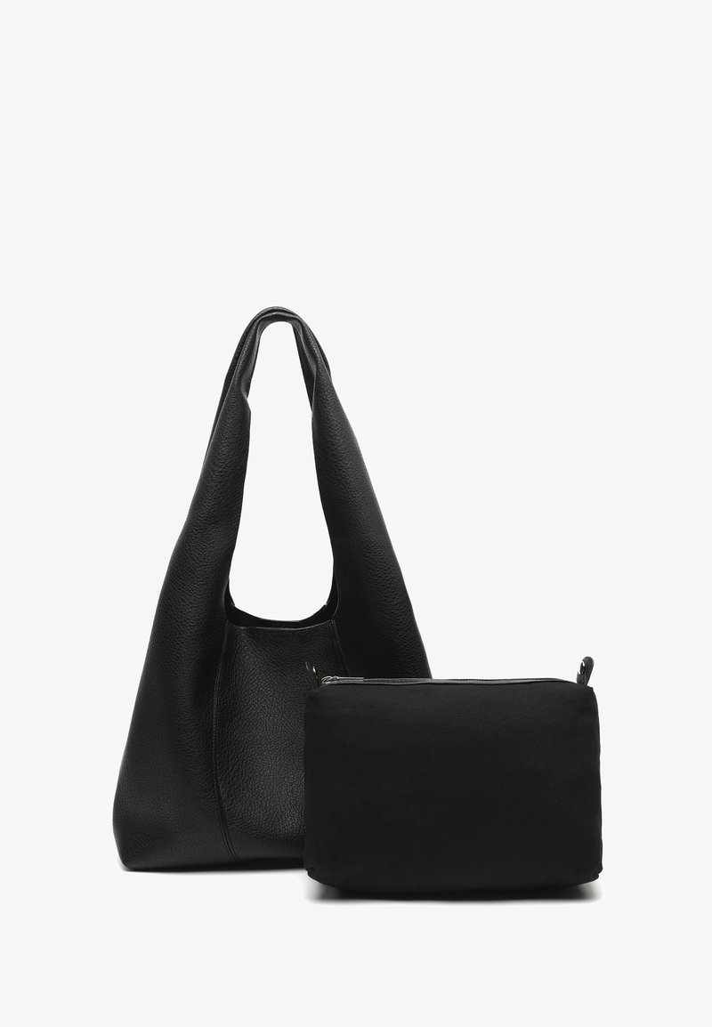 Miękka czarna skórzana torba na ramię z szerokim paskiem obok mniejszej czarnej saszetki na zamek na białym tle.