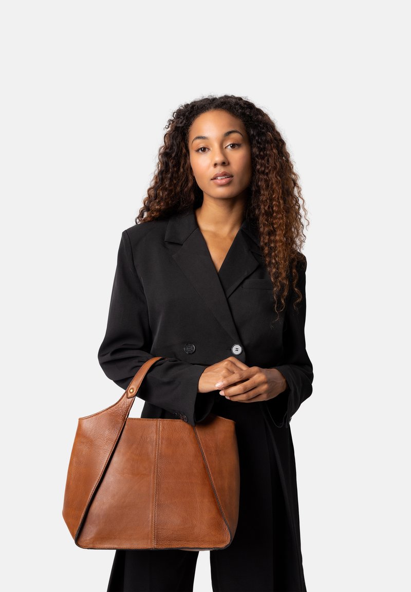 Bolsa tote de cuero marrón con un diseño estructurado y una sola correa para el hombro, que presenta costuras visibles y una superficie texturizada.