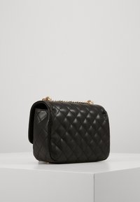 Borsa a tracolla nera in pelle trapuntata con forma rettangolare, base piatta, accessori in catena dorata e una texture liscia.
