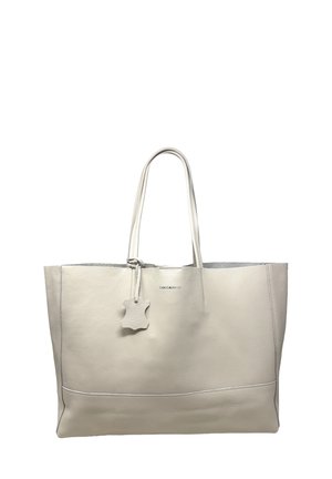 Borsa a mano in pelle beige con due spallacci e una targhetta in pelle appesa vicino al centro superiore.
