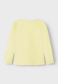Langarmshirt van zacht gele stof. Heeft een ronde halslijn en geraffineerde details op de schouders. Glad, semi-pasvormig ontwerp.