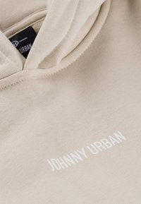 Beżowa bluza z kapturem z teksturowanej, miękkiej tkaniny. Z przodu znajduje się białe haftowane logo "JOHNNY URBAN". W zestawie kaptur ze sznurkiem.