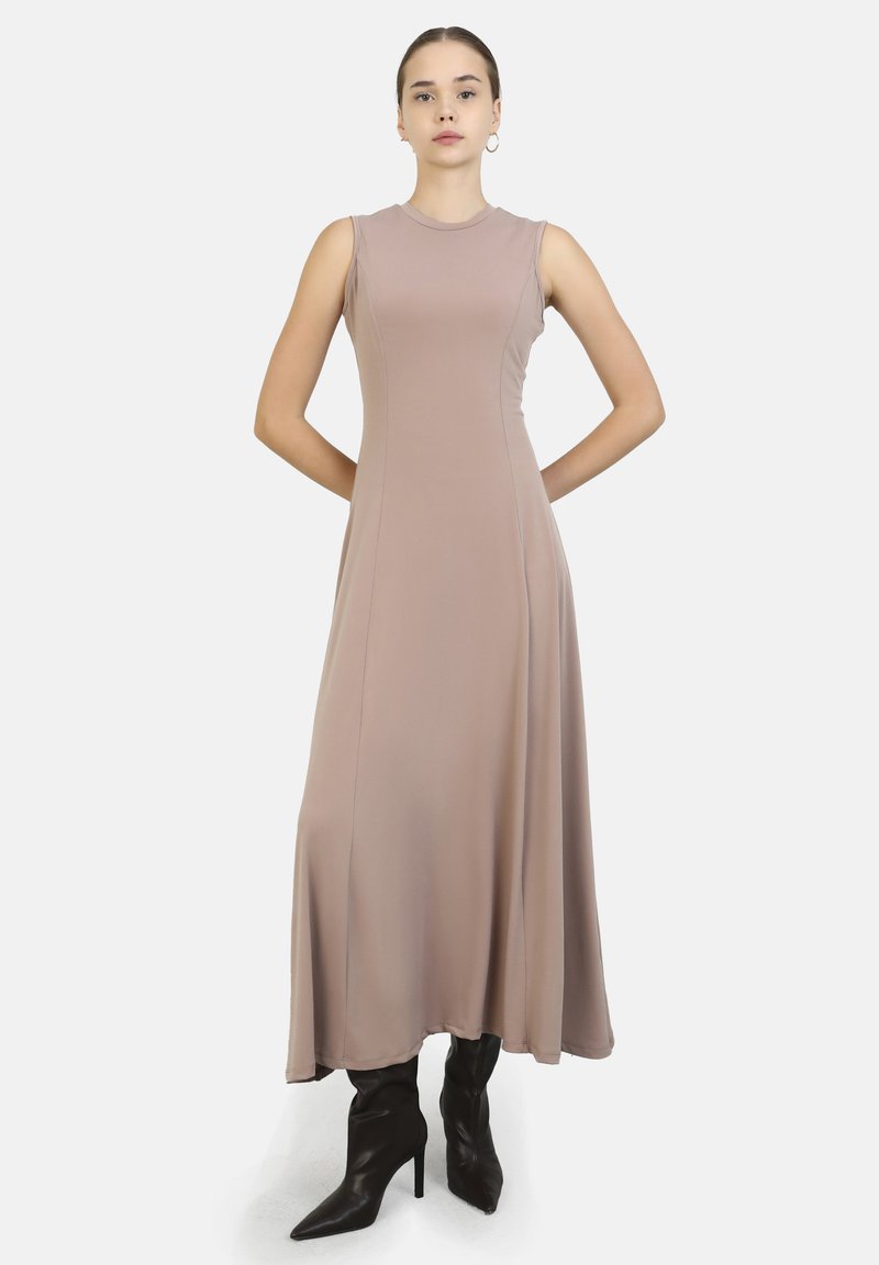 Midi-mekko vaaleasta taupe-kankaasta, jossa on tiukka yläosa ja levenevä hame. Hihaton malli, jossa pyöreä pääntie. Yhdistetty mustiin nilkkasaappaisiin.