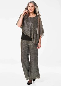 Un abbigliamento metallico argento e nero che presenta un top poncho ampio e fluente e pantaloni a gamba larga con una finitura texture lucida. Scarpe nere completano l'aspetto.