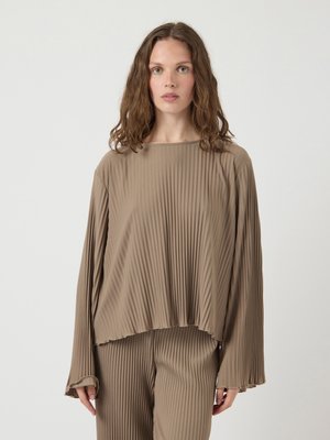 Langsleeve, geplooid shirt in beige, met een losse pasvorm en een ronde hals. Zachte textuur met subtiele franjes aan de mouwen en de zoom.
