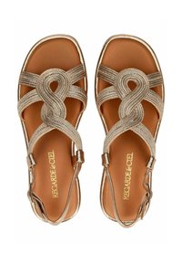 Goldene geflochtene Sandalen mit einem überkreuzten Riemendesign, verstellbarem Knöchelriemen und einem braunen Fußbett. Glatte Textur mit metallischen Akzenten.