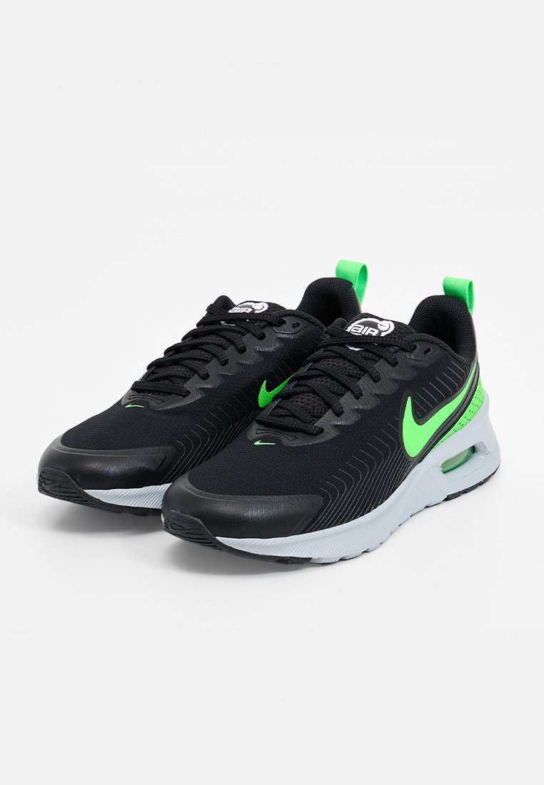 Schwarze Sport Schuhe mit grünen Akzenten, strukturiertem Mesh-Obermaterial und gepolsterten Sohlen. Merkmale einen auffälligen Nike-Swoosh und ein Schnürdesign.