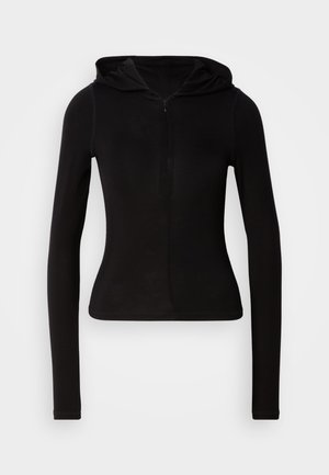 Sudadera negra de manga larga con capucha y cremallera frontal. Confeccionada en una tela suave, de diseño ajustado y con un detalle mínimo. Tiene un dobladillo redondeado en la parte inferior.