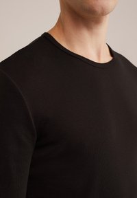 Fekete hosszú ujjú póló, kerek nyakkivágással, bordázott anyagból készült, testhezálló szabású, sima tapintású, minta és látható fémalkatrészek nélkül.