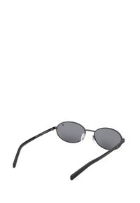 Oválné sluneční brýle s tmavě šedými skly, tenkým černým kovovým rámem a průhlednými nosními podložkami. Lehký design s jemně zakřivenými stranicemi.
