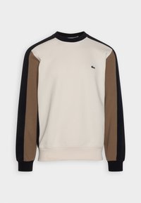 Sudadera de cuello redondo color crema con mangas raglán en marrón y negro. Presenta un pequeño logo verde en el pecho. Hecha de una tela suave y texturizada.