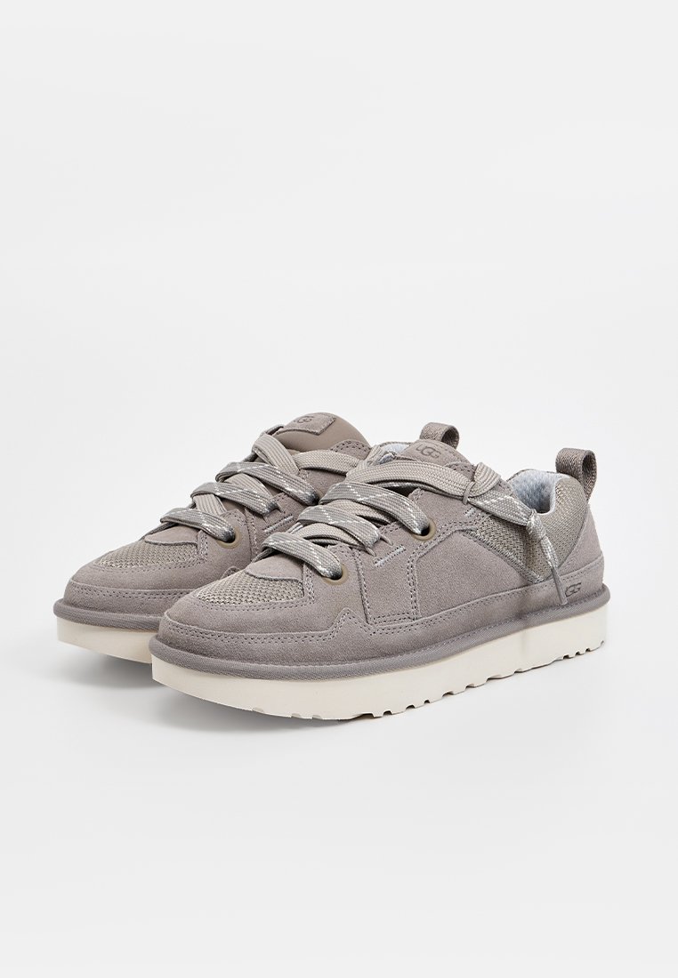 Grijze sneakers van suede en mesh materialen, ronde neus, gestructureerde bovenkant, platte veters en een contrasterende witte zool.