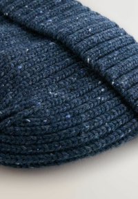 Knitted navy blue wool beanie with a ribbed texture and subtle flecks of lighter color, featuring a folded brim design.
