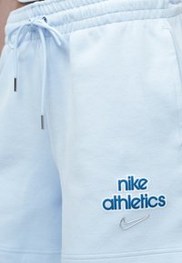 Σετ ανοιχτό μπλε βαμβακερές βερμούδες με ελαστική μέση και ρυθμιζόμενο κορδόνι. Διαθέτουν λογότυπο "nike athletics" σε μπλε και ασημένιο σήμα Nike.