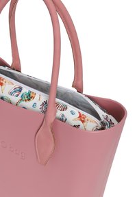 Różowa torba na ramię z gładkiego, gumopodobnego materiału. Ma smukłe uchwyty, wzorzystą wewnętrzną kieszeń z grafikami muszelek oraz zamek błyskawiczny.