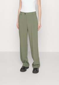 Pantaloni tailorati verde oliva con una vestibilità morbida, dotati di chiusura con bottone e passanti per la cintura. Tessuto liscio con una leggera lucentezza.