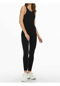 Body negro con un diseño ajustado, corte sin mangas y tejido elástico. Combinado con zapatillas blancas. Apariencia simple y elegante.