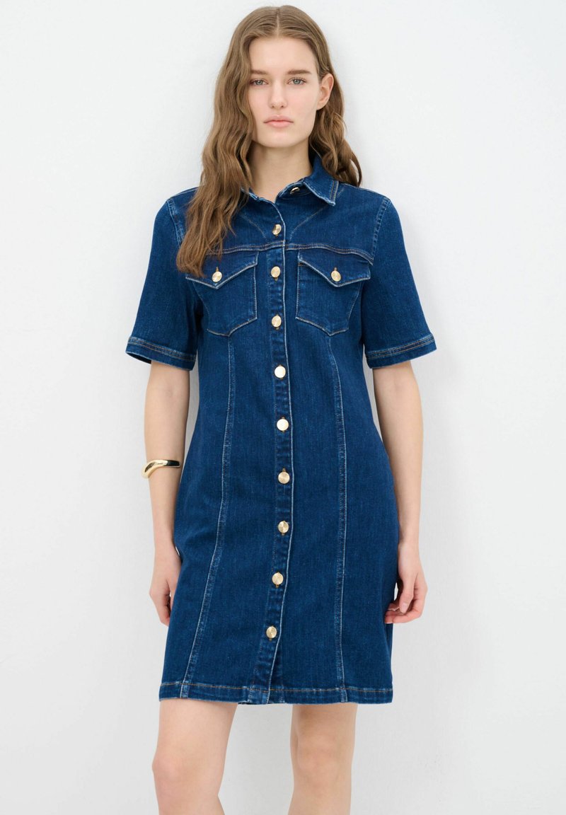 Denim-tyylinen mekko, tummansininen, lyhyet hihat, napit edessä, kaksi rintataskua, kultaiset napit ja näkyvät ompelusaumat.