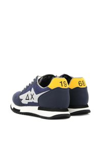 Sneakers sportivi in navy con accenti bianchi e gialli, dotati di una suola testurizzata, design angolare e dettagli con logo sul lato.