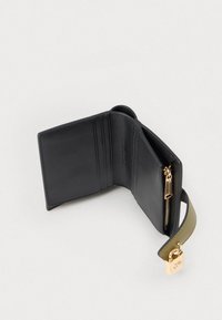 Μαύρο δερμάτινο πορτοφολάκι ανοιχτό που δείχνει υποδοχές καρτών, μια με γρίλια τσέπη και ένα προσαρτημένο πράσινο λουρί με χρυσό γούρι κλειδώματος.