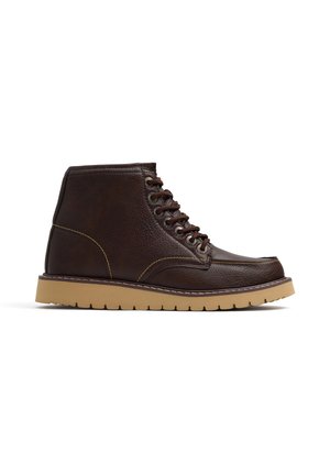 Bota de cuero marrón oscuro con cordones, costuras amarillas y suela de goma color tostado, vista de perfil sobre un fondo blanco.