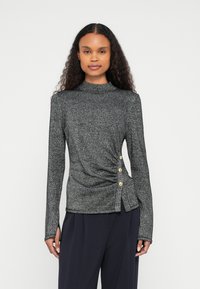 Szary top z długim rękawem z wysokim dekoltem, zawiązany materiał, złote guziki po boku oraz lekko asymetryczny dół.