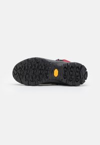 Suola di scarpa da trekking nera con scanalature profonde e aggressive e un logo Vibram giallo. Materiale in gomma con un motivo di grip testurizzato per una migliore aderenza.