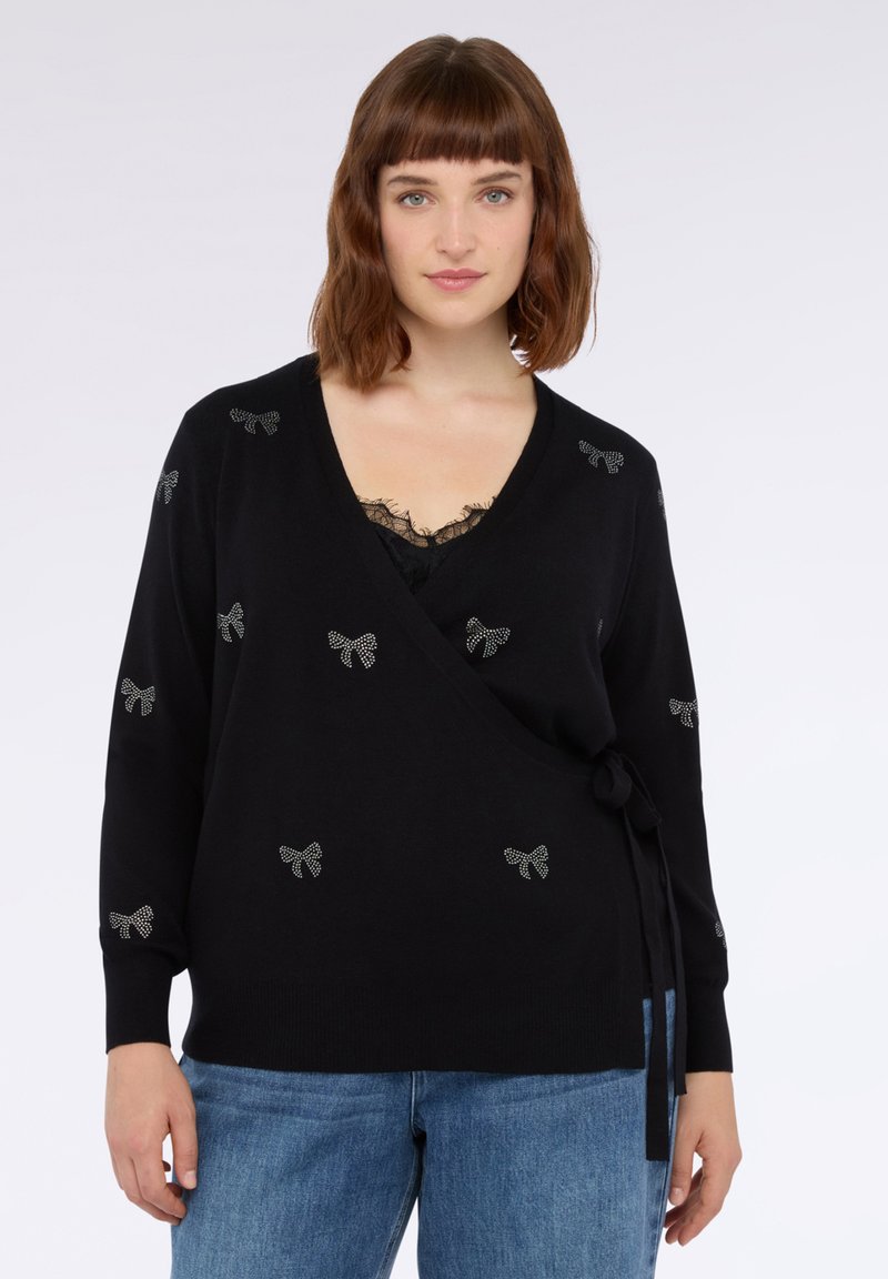 Svart insvepningströja med långa ärmar, prydd med silverfärgade rosettdekorationer, djup V-ringning och knytdetalj vid midjan. Mjuk stickad tyg.