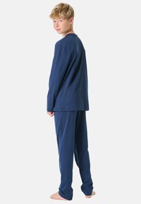 Top a maniche lunghe blu navy e pantaloni abbinati realizzati in un tessuto morbido e liscio. Il design presenta una vestibilità comoda e cuciture minimali.