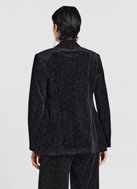 Schwarze Samtblazer mit taillierter Silhouette, die über eine dezente Textur und ein Diamantmuster verfügt, sowie einen ein-knopf-Verschluss in der Taille.