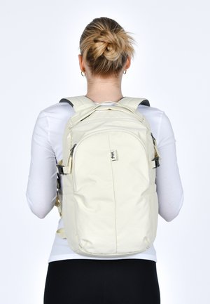 Zaino in nylon beige con spallacci imbottiti, multiple tasche con zip e un design strutturato. Cinghia toracica regolabile inclusa.