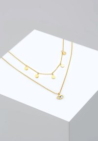 Guld-tone lagdelt halskæde med kædedesign, små runde vedhæng og et øjeformet vedhæng med en blå sten accent.