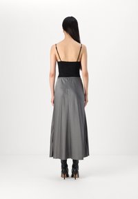 Black lace camisole with thin straps, paired with a long, flowing silver satin skirt. Boots feature a textured surface and pointy heels.