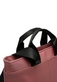Pink tote bag with a sleek design, featuring smooth material, black fabric handles, and visible stitching along the edges.