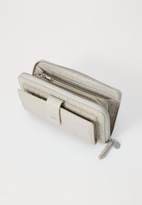 Beige zip wallet with multiple compartments, dotted pattern, smooth texture, and silver hardware. Includes a detachable charm and closure tab.