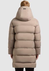 Beige pufferjakke med hætte, der har vandrette quiltede sektioner og en glat tekstur. Indeholder et lille logo på bagsiden af hætten.