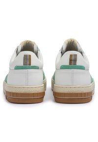 Sneakers bianchi in pelle con dettagli in suede verde, che presentano una suola in gomma testurizzata, decorazioni a righe sul tallone e un marchio sul lato.
