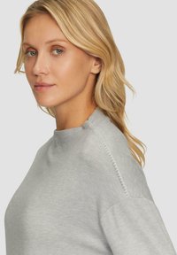 Helles graues Sweatshirt mit hohem Kragen, das über eine gerippte Textur und seitliche Nähte verfügt. Das schlichte Design ermöglicht vielseitige Styling-Optionen.
