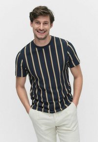 Marine gestreept T-shirt met horizontale strepen in beige, oranje en wit. Korte mouwen en een ronde halslijn, gedragen met lichte broeken.