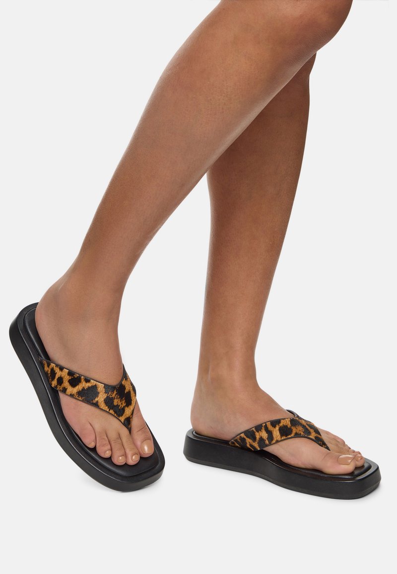 Kožené žabky s páskem v leopardím vzoru a silnou černou podrážkou. Design zahrnuje pásek mezi prsty a polstrovanou stélku pro komfort.